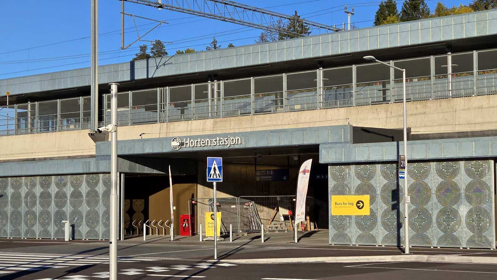 Inngangen til nye Horten stasjon på Viulsrød med gult skilt for buss for tog ved fasaden